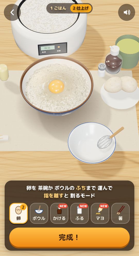 プレイ中の画面。茶碗に盛ったごはんのくぼみに卵を割り入れたところ。下に卵・ボウル・かける・ふる・マヨ・箸の道具と「完成！」ボタン